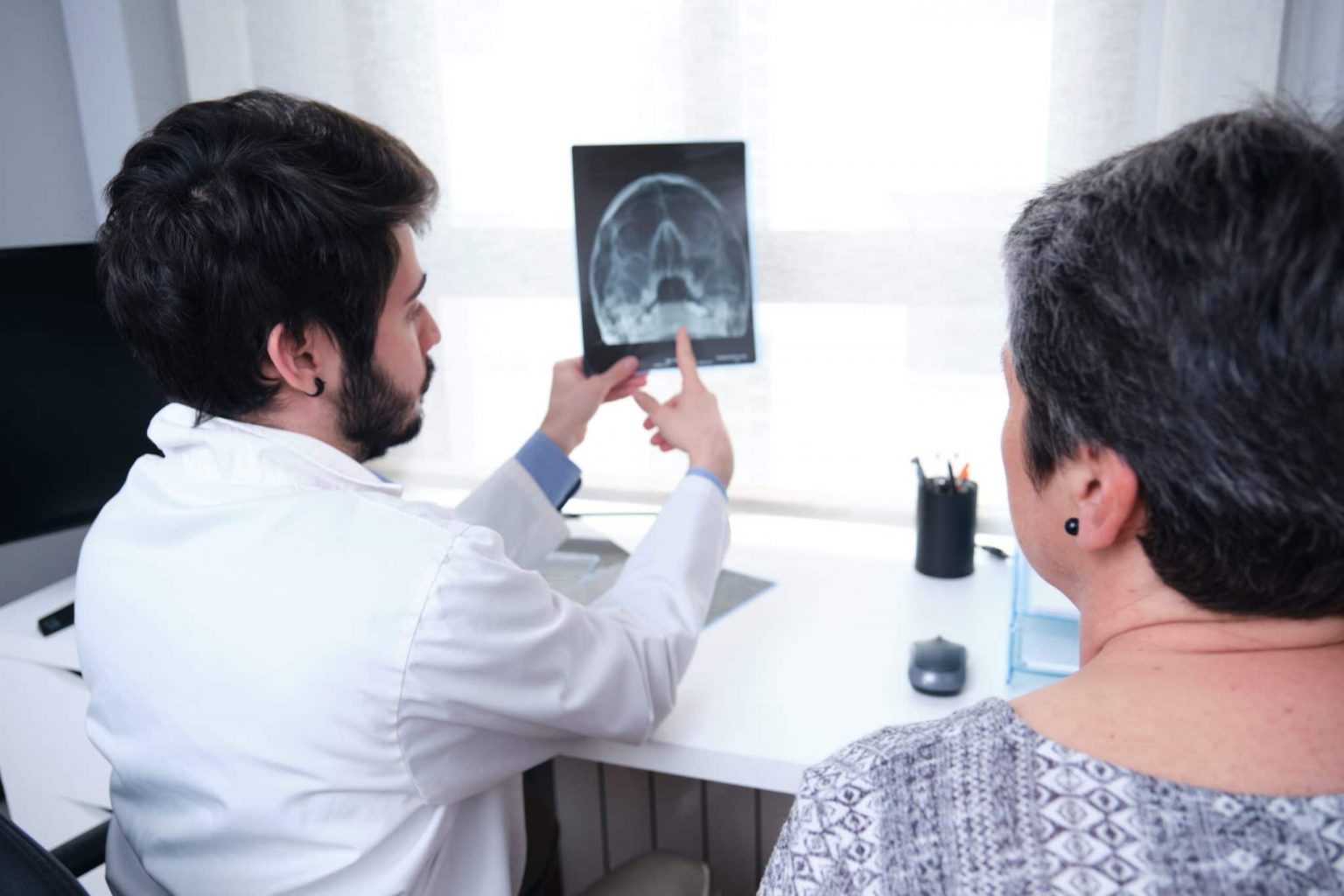 Sinus Surgery Xray Doctor pointing to an x-ray of the sinuses while patient looks.