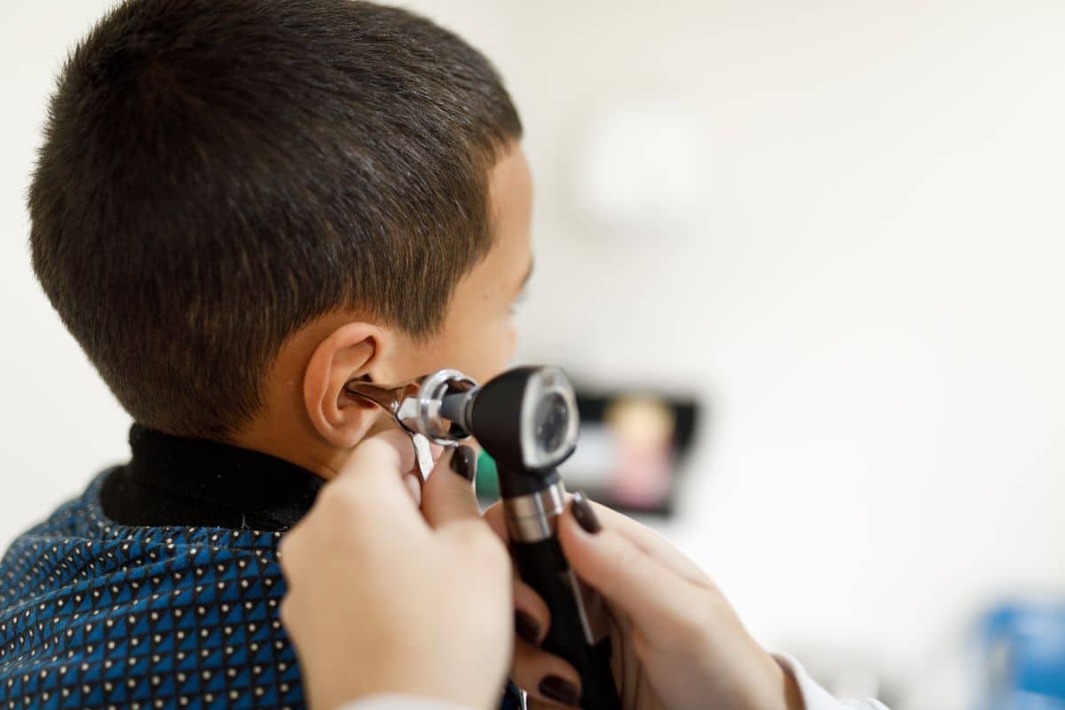 pediatric-ear-infection-symptoms Doctor using a medical device to inspect the inner ear of a child patient